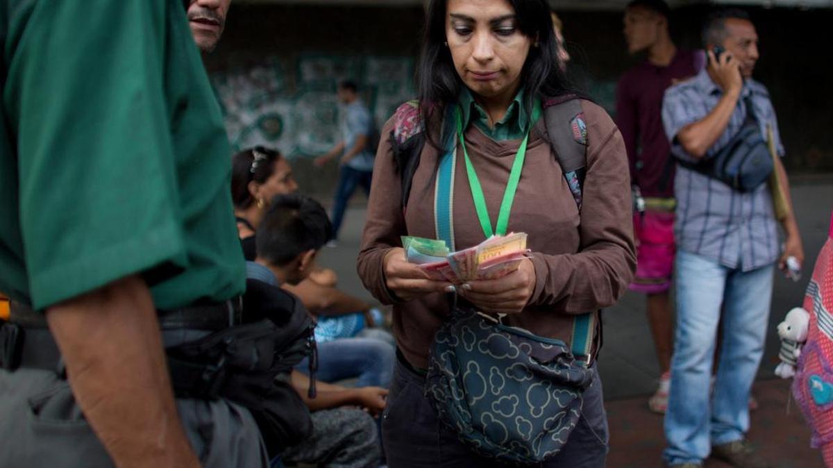 Una empleada del transporte público cuenta el dinero que ha recaudado de los pasajeros en Caracas, Venezuela, el 21 de agosto del 2018.