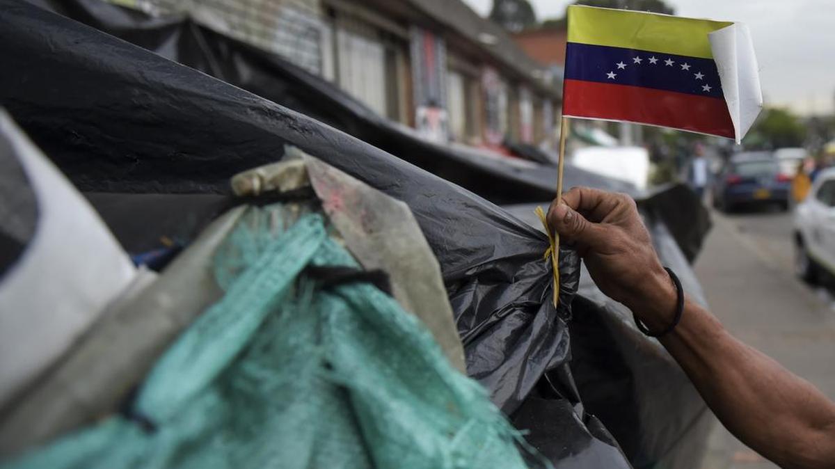 Un migrante venezolano tiene una bandera nacional en un campamento improvisado cerca de una terminal de autobuses en Bogotá el 9 de noviembre de 2018.