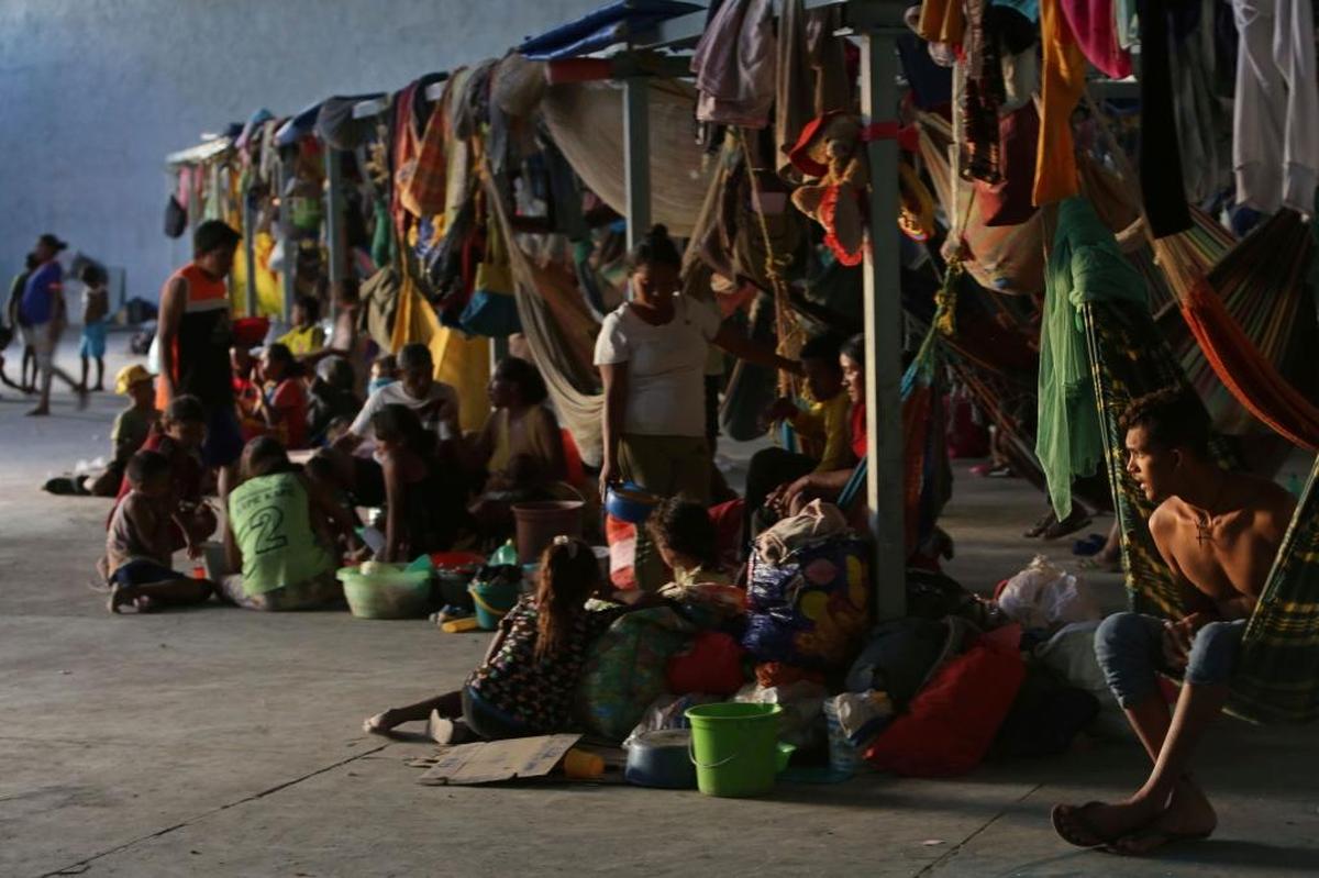 Refugiados esperan sentados en el suelo en Pacaraima, la principal entrada en Brasil de los que escapan de la aguda crisis en Venezuela.