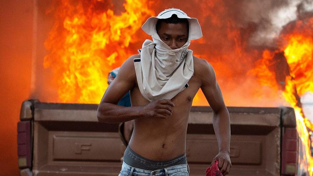 Una persona corre durante enfrentamientos entre antichavistas y miembros de la Guardia Nacional Bolivariana de Venezuela este sábado en el paso fronterizo ubicado en la localidad de Pacaraima (Brasil), en el límite fronterizo entre Brasil y Venezuela, cerrado desde el jueves por orden del Gobierno de Nicolás Maduro.
