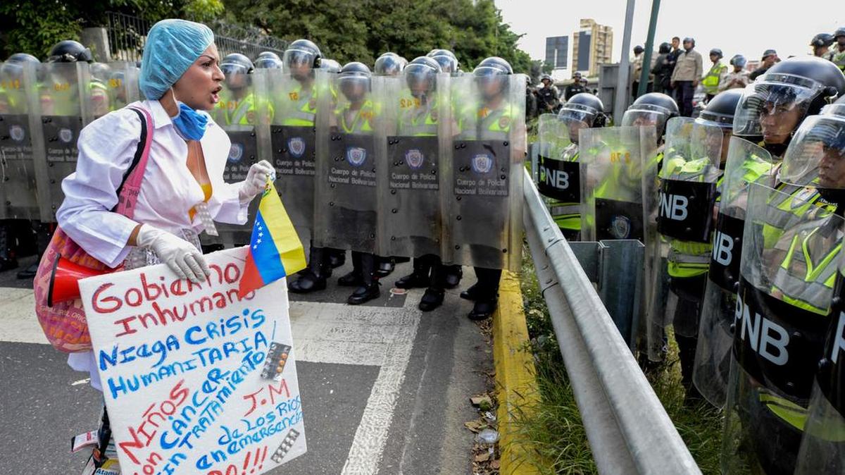 Una trabajadora de la salud que lleva una pancarta se enfrenta a agentes de policía durante una manifestación contra el presidente Nicolás Maduro del gobierno, por la falta de medicamentos y bajos salarios en el país, en Caracas el 7 de febrero de 2017.