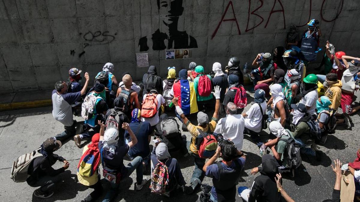Un grupo de personas rinde homenaje al joven de 17 años Neomar Lander, quien murió el pasado miércoles durante protestas opositoras, en frente de un grafiti pintado en su honor durante una manifestación el viernes 9 de junio de 2017, en Caracas, Venezuela.