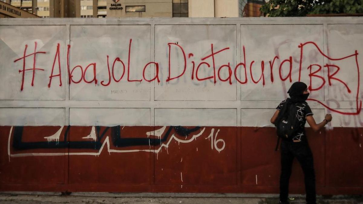 Un manifestante opositor permanece en frente de un grafiti durante una protesta el martes 18 de julio de 2017, en Caracas (Venezuela).