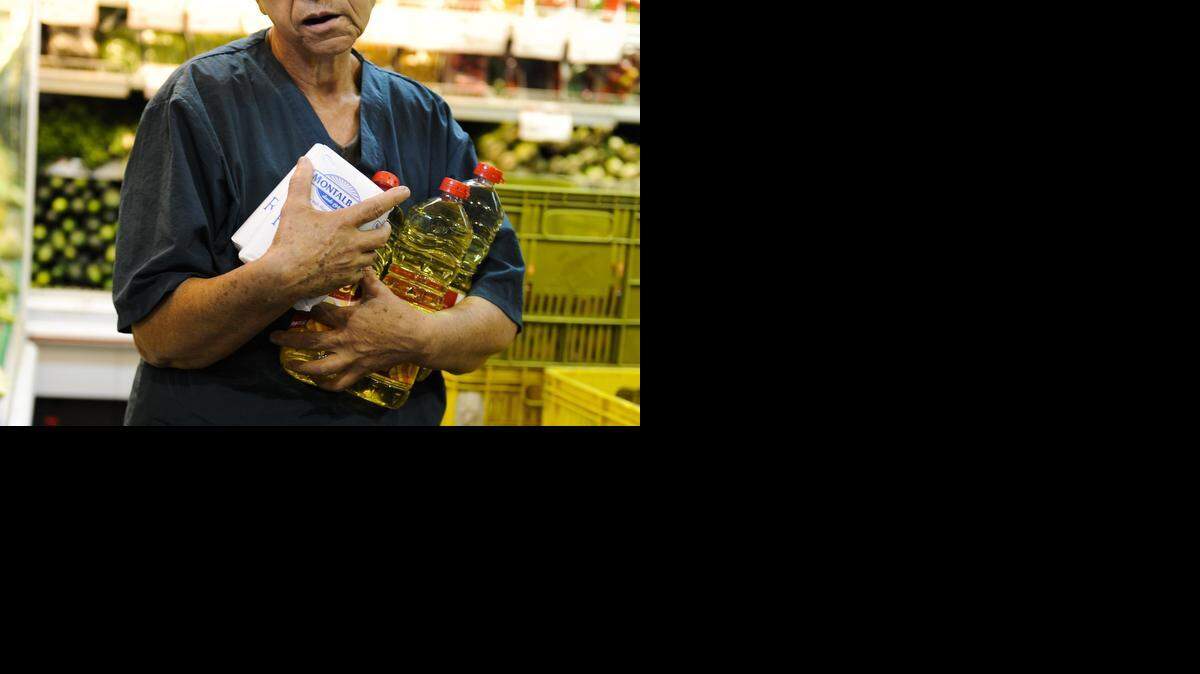 
Una mujer sostiene paquetes con botellas de aceite y azúcar en un supermercado en Caracas, el 22 de noviembre de 2011. 
