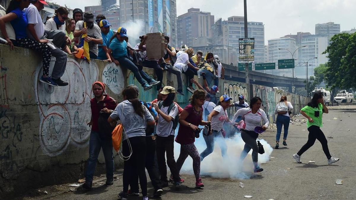 Manifestantes saltan un muro para huir de los gases lacrimógenos, el miércoles 19 de abril de 2017, en Caracas, Venezuela.