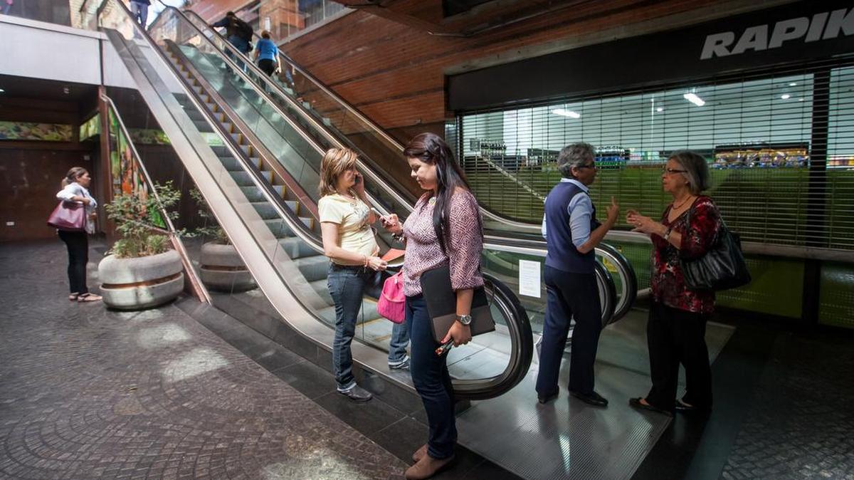 Clientes de un centro comercial suben por las escaleras eléctricas, apagadas por el racionamiento, el miércoles 10 de febrero de 2016, en Caracas (Venezuela).