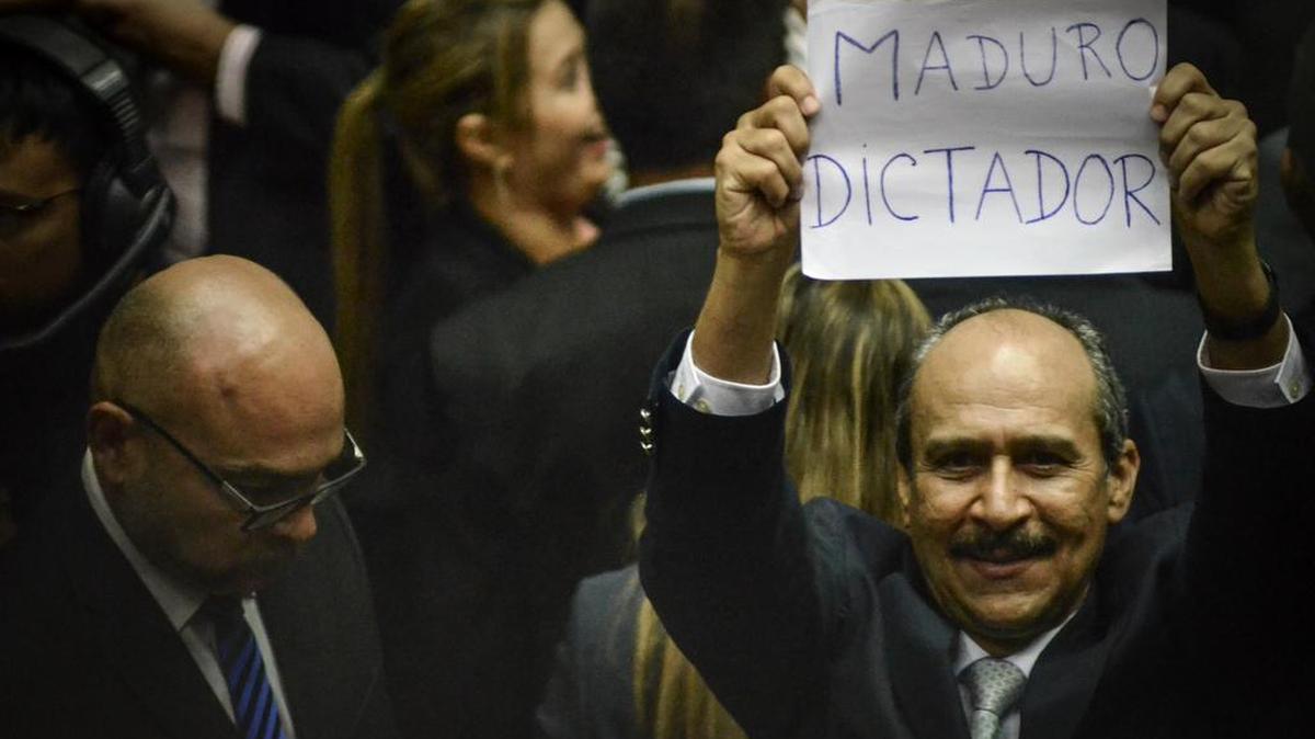 Un diputado de la Asamble Nacional en Venezuela levanta un cartel contra el presidente del país.