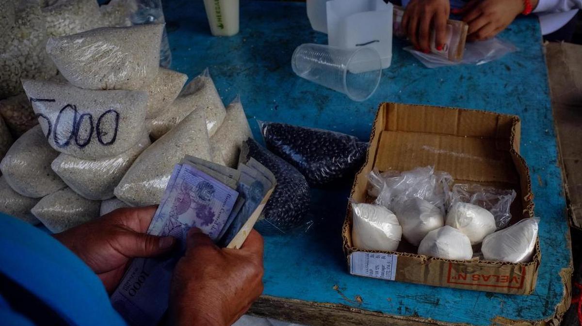 Una mujer vende pequeñas bolsas de leche en polvo en un puesto informal en una calle de Caracas.