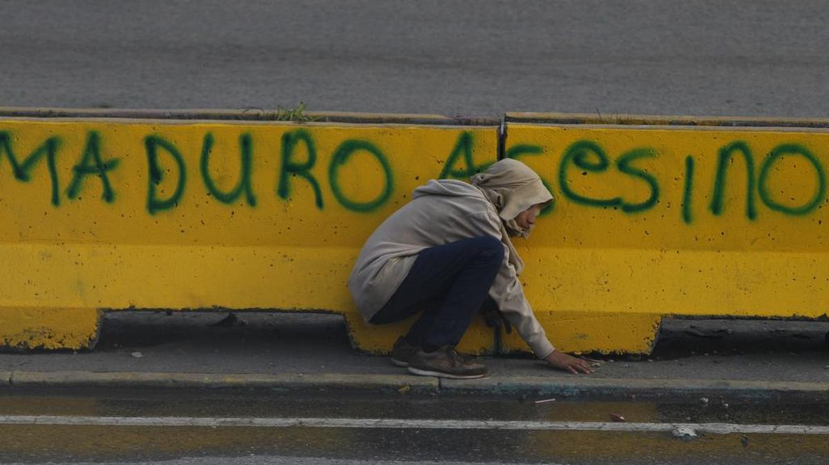 Un manifestante se esconde de la policía venezolana durante una protesta en las inmediaciones de la base de La Carlota, en Caracas.
