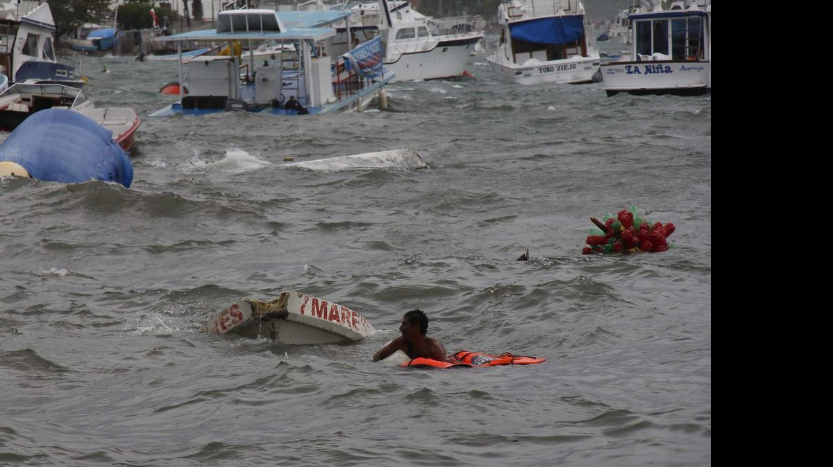 
Un hombre intenta rescatar pertenencias entre las embarcaciones afectadas por el huracán Carlos el domingo 14 en el puerto de Acapulco, México. 
