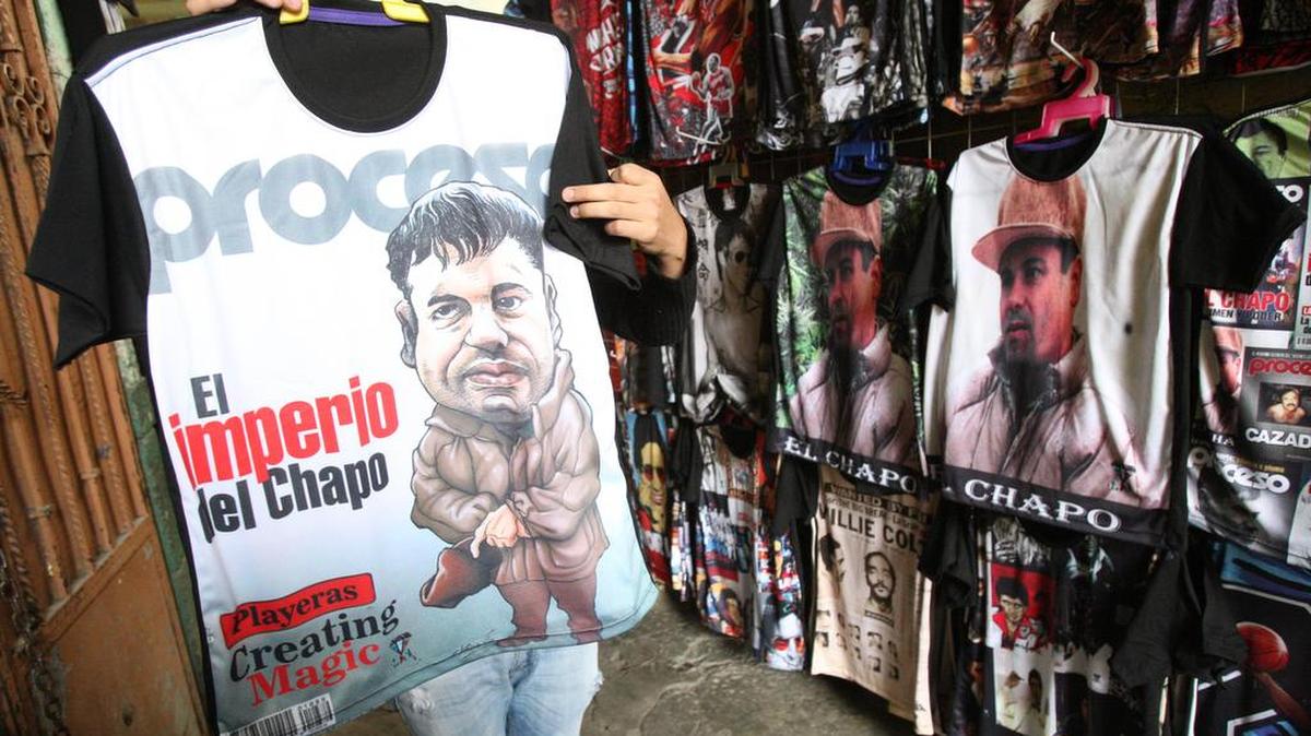 Un vendedor muestra una camiseta con la imagen Joaquín "el Chapo" Guzmán que es ofertada en el mercado de Tepito el lunes 18 de enero de 2016, en Ciudad de México, donde junto con otros productos como gorras con la leyenda "King Chapo" son un jugoso reclamo para las ventas.