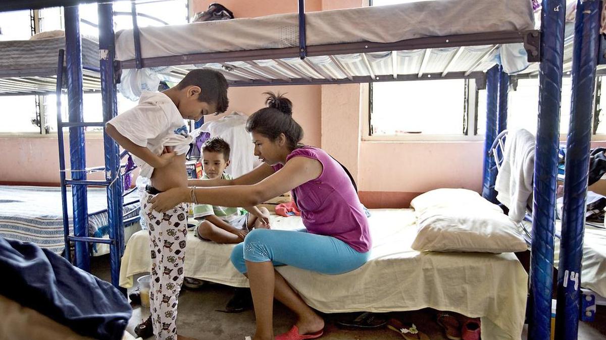 Marilyn Barahona, 26, que viaja desde Tegucigalpa con su esposo y dos hijos, le prueba algunas ropas de donación a uno de los niños.