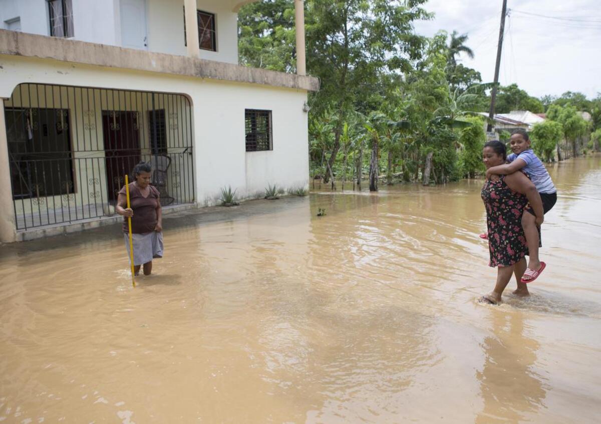 Varias personas caminan por una calle inundada hoy, viernes 22 de septiembre de 2017, tras el paso del huracán María en la ciudad de Nagua, República Dominicana. Un total de 38 localidades de República Dominicana siguen aisladas a causa del desbordamiento de ríos, arroyos y cañadas que provocó el huracán María.