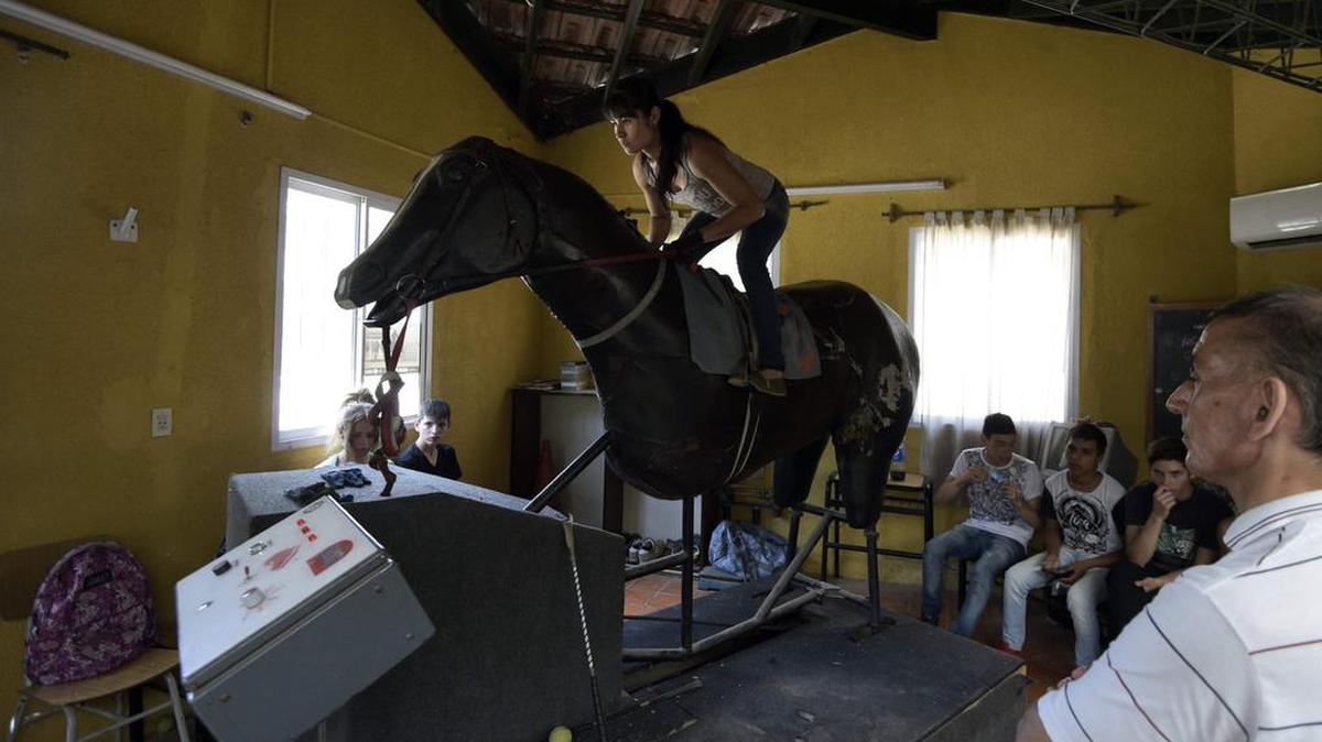 El profesor Jorge Caro Araya entrena a Romina Villegas mientras practica en el caballo de carreras mecánico en la escuela en el Jockey Club de San Isidro en las afueras de Buenos Aires, el 5 de diciembre de 2016.