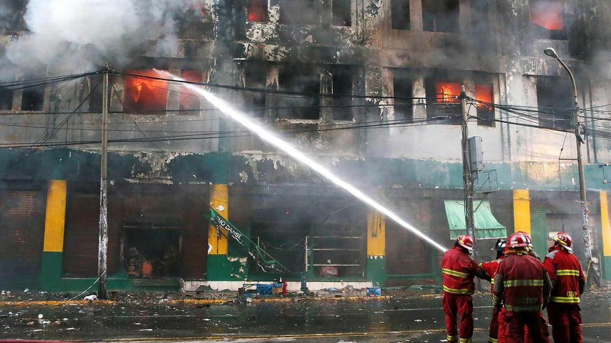 Fotografía cedida por la Agencia Andina, de un grupo de bomberos trabajando por extinguir un incendio desatado en el edificio de una antigua fábrica, ocupado actualmente por galerías de productos de ferretería, el viernes 23 de junio de 2017, en Lima, Perú.