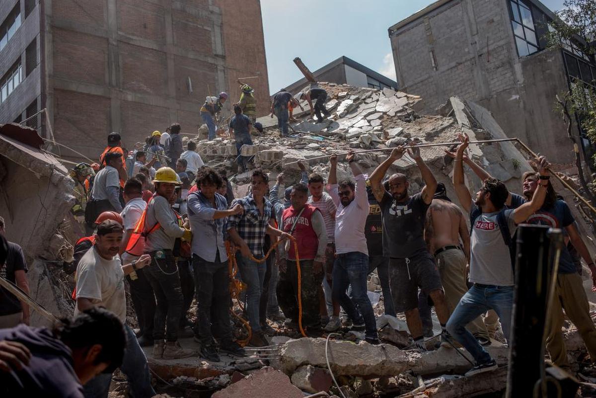 Varias personas eliminan escombros de un edificio derrumbado luego de un terremoto en la Ciudad de México el 19 de septiembre de 2017.