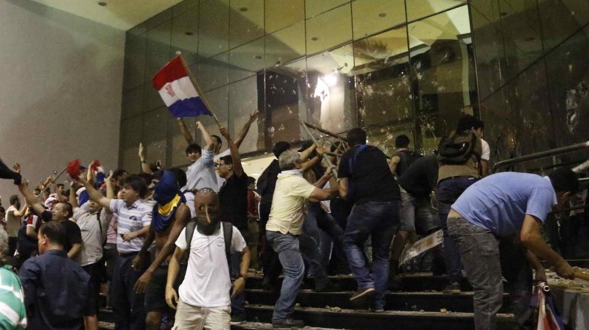 Manifestantes atacan la sede del Congreso Nacional en Asunción (Paraguay) el viernes 31 de marzo de 2017, después de que hoy un grupo de 25 senadores aprobó el proyecto de enmienda constitucional para habilitar la polémica reelección presidencial.