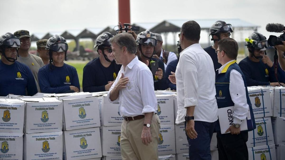 El presidente de Colombia, Juan Manuel Santos (izq.), y su homólogo ecuatoriano Rafael Correa (der.), saludan el domingo a bomberos que custodian la ayuda otorgada por el gobierno colombiano para los damnificados del terremoto.