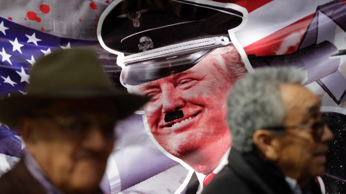 José Luis Gonzólez Meza (der.), uno de los abogados del narcotraficante Joaquín ‘El Chapo’ Guzmán, y José Puente León frente a un cartel con una imagen de Donald Trump imitando a Hitler.