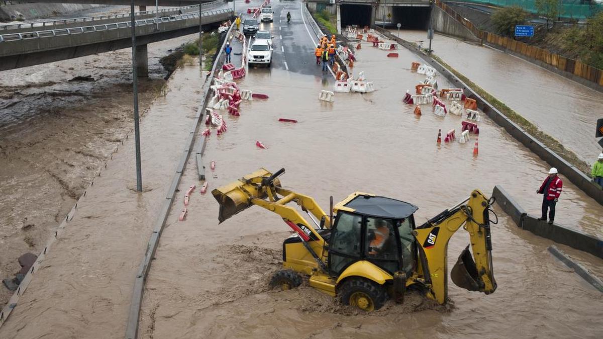 Una maquinaria trabaja en el medio de una calle inundada en Santiago, Chile, el domingo, 17 de abril de 2016. Las autoridades dicen que el Río Mapocho inundó varios distritos de la ciudad y deslizamientos de tierra mataron al menos a una persona.