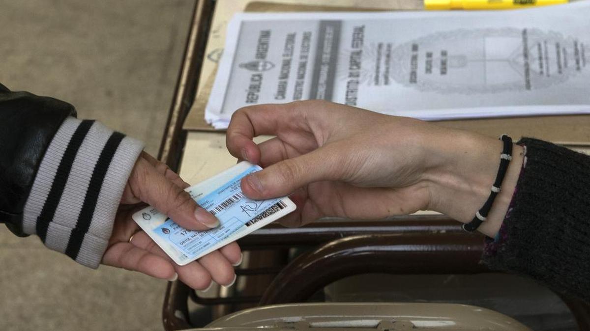 Un funcionario de la mesa de votación devuelve la identificación y un recibo de votación a un votante durante las elecciones legislativas primarias en Buenos Aires el 13 de agosto de 2017.