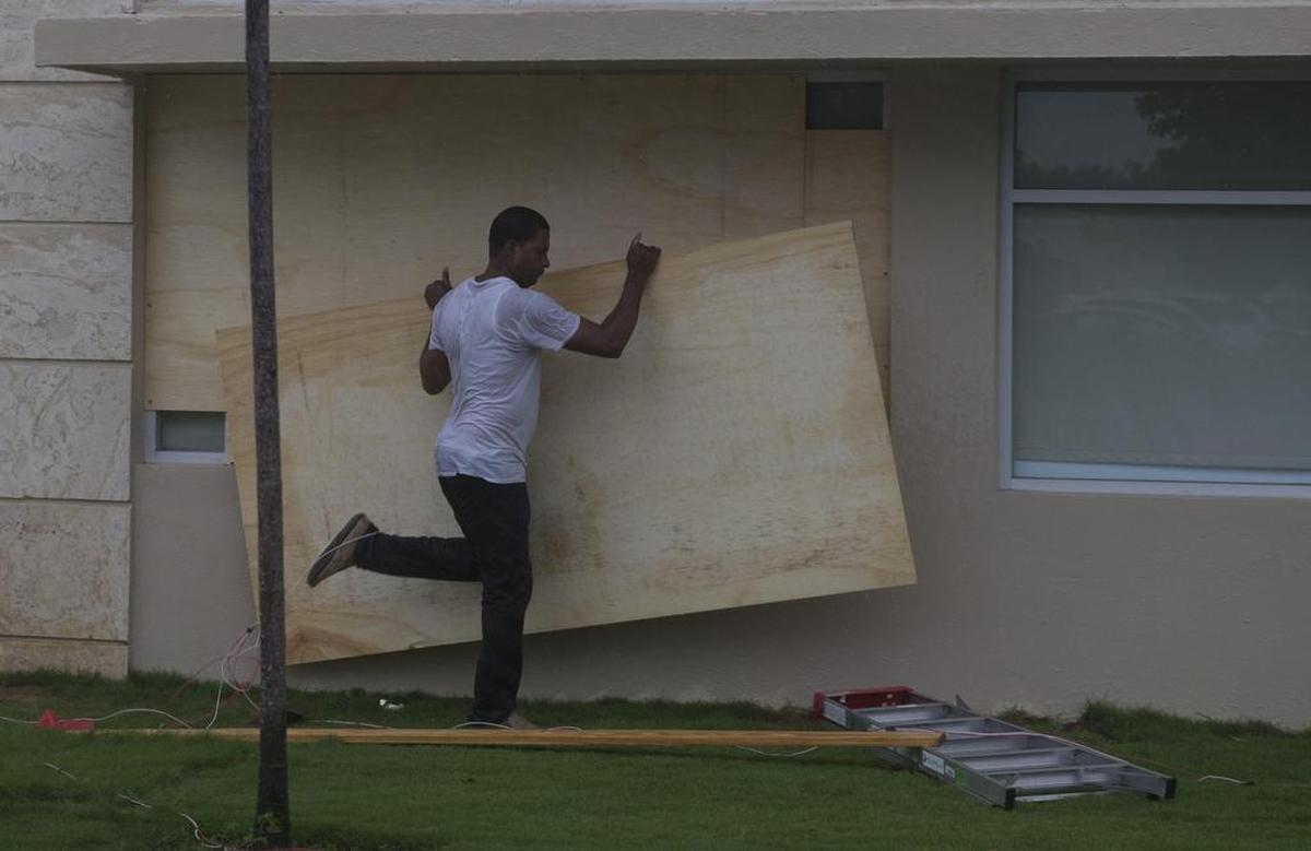Trabajadores cubren los ventanales de un banco horas antes del paso del huracán María el miércoles 20 de septiembre de 2017, en Punta Cana.