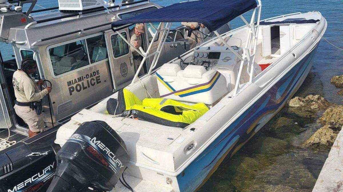 Una lancha patrulla de la policía del Condado Miami-Dade está amarrada junto a una embarcación con consola central que, según los agentes federales, se utilizó para llevar al menos a tres migrantes a la costa en Key Biscayne, cerca de Miami, el lunes 4 de diciembre de 2023.