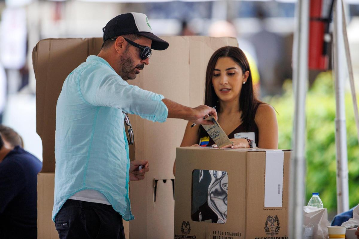 Una trabajadora electoral asiste a Juan Andrés García, oriundo de Bogotá, durante la segunda vuelta de la elección presidencial colombiana, el domingo 19 de junio de 2022, en el Consulado General de Colombia en Coral Gables, Florida.