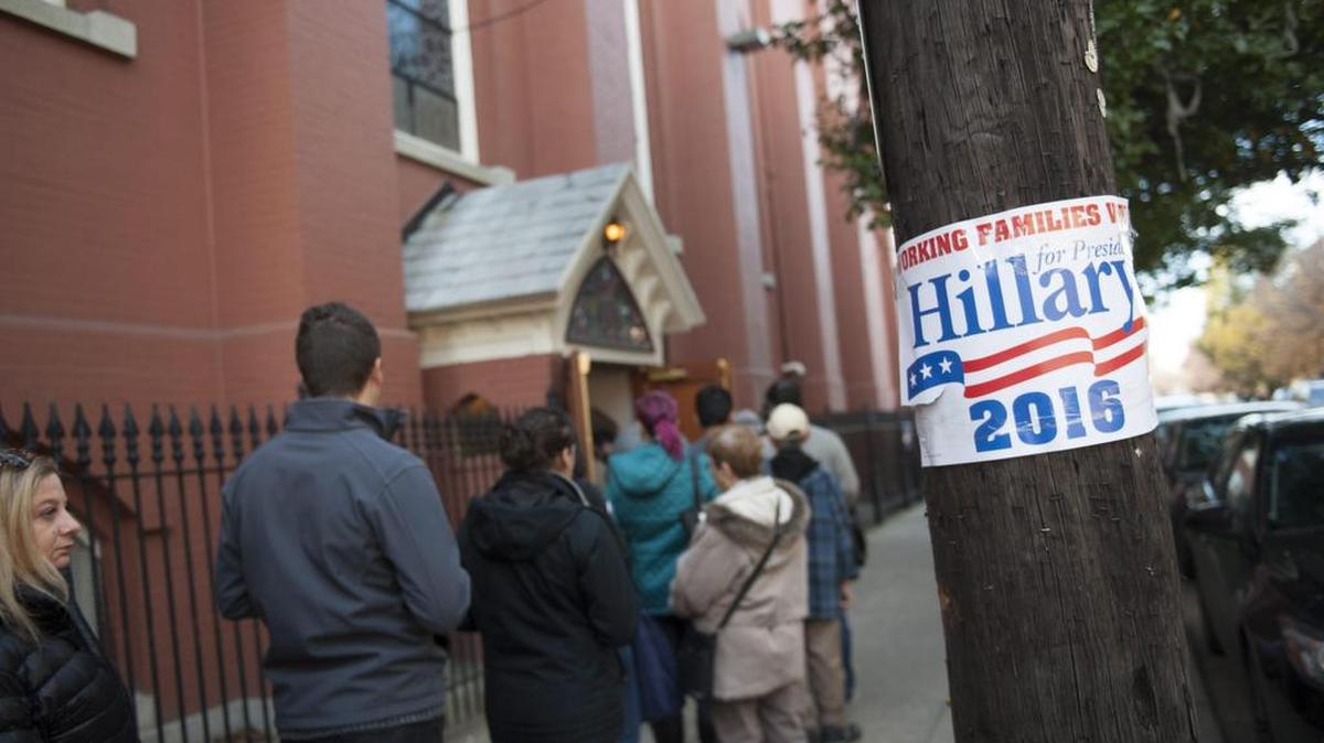 Varias personas hacen cola ante un cartel electoral de la candidata Hillary Clinton en un colegio electoral de Philadelphia, Pennsylvania, Estados Unidos hoy 8 de noviembre de 2016.