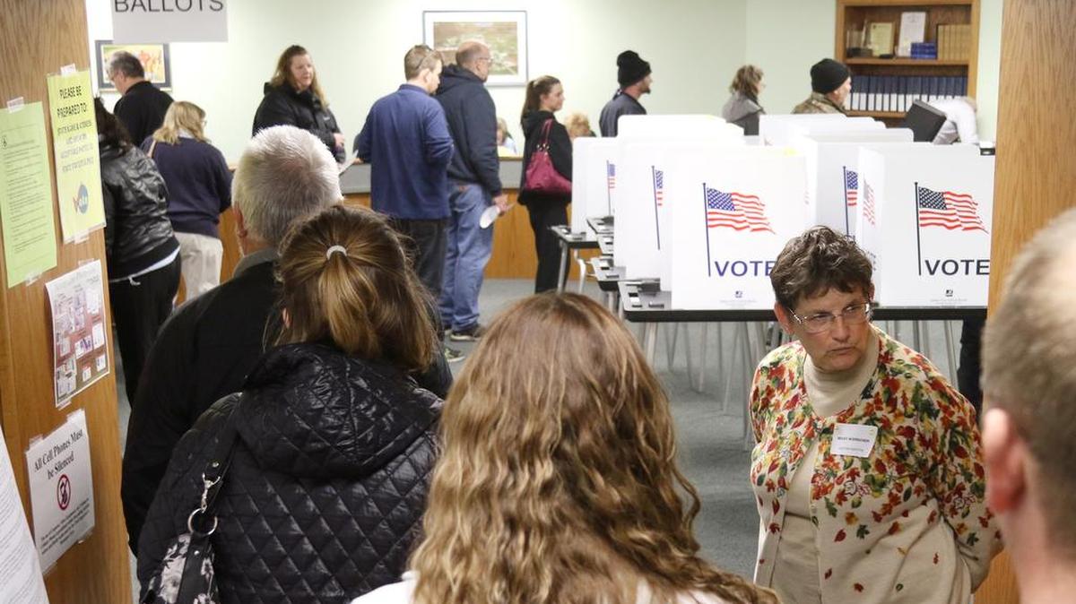 La inspector de elecciones Becky Wierschem, a la derecha, mira para ver cuán larga es la línea de votantes se extiende en el Village Hall el día de las elecciones, el martes, 8 de noviembre de 2016 en la aldea de Jackson, Wisconsin.