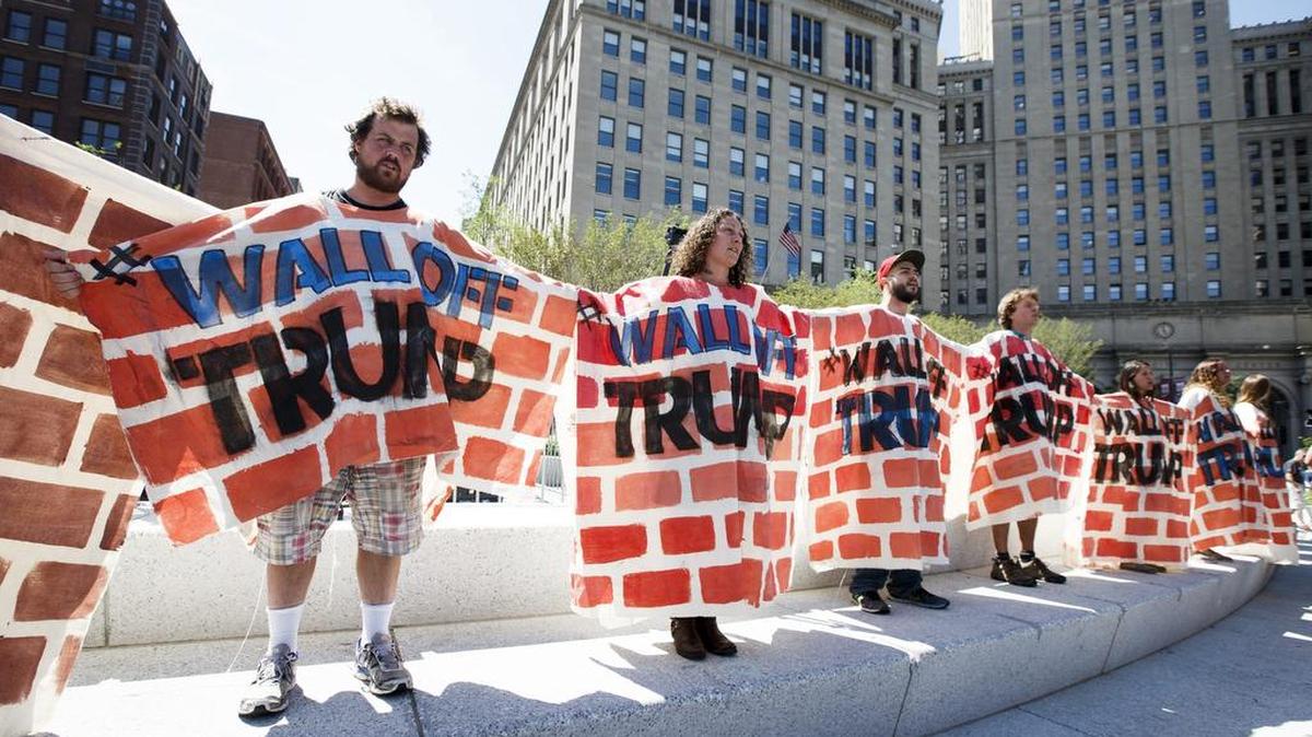 Unos manifestantes vestidos como murrallas forman una cadena humana, durante una manifestación llamada "Wall Off Trump" (Amurrallar a Trump) realizada en la plaza Pública de Cleveland en Ohio.