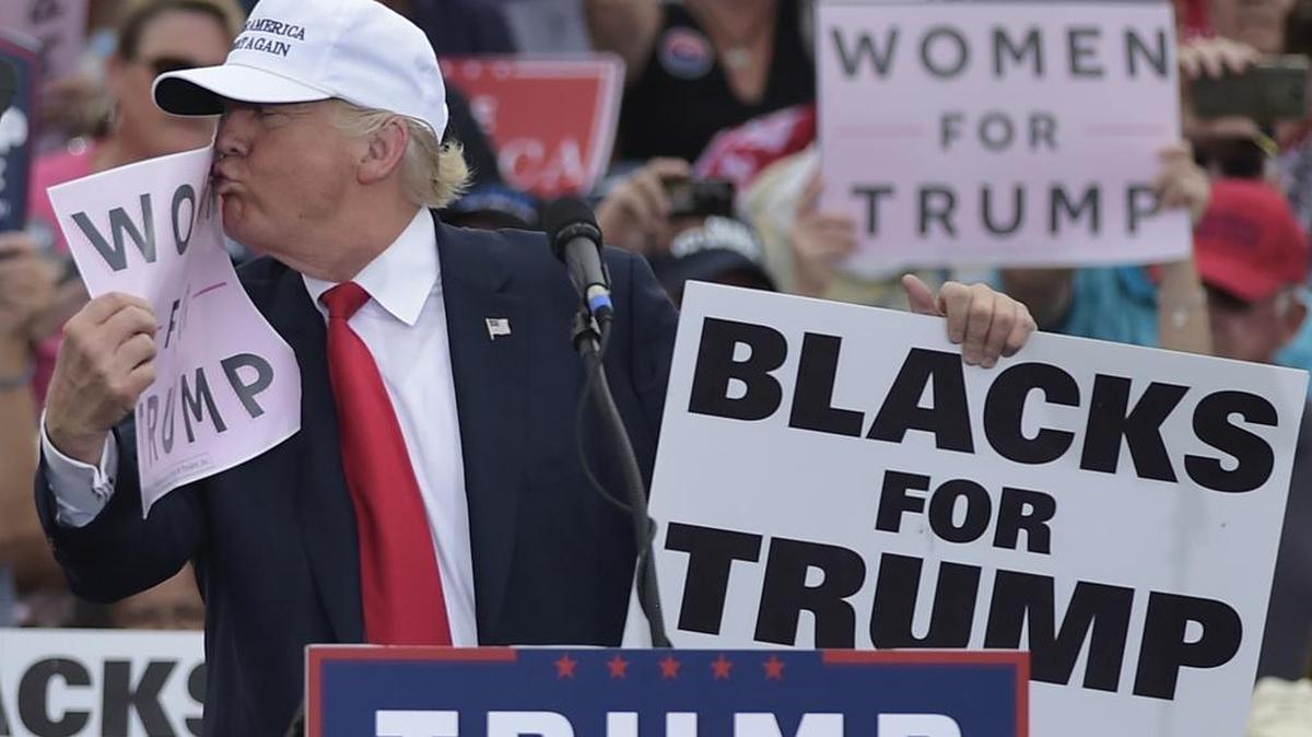 El candidato presidencial republicano Donald Trump besa una pancartaque dice "Mujeres por Trump" durante una manifestación en el Aeropuerto Regional de Lakeland, en Florida el 12 de octubre de 2016.