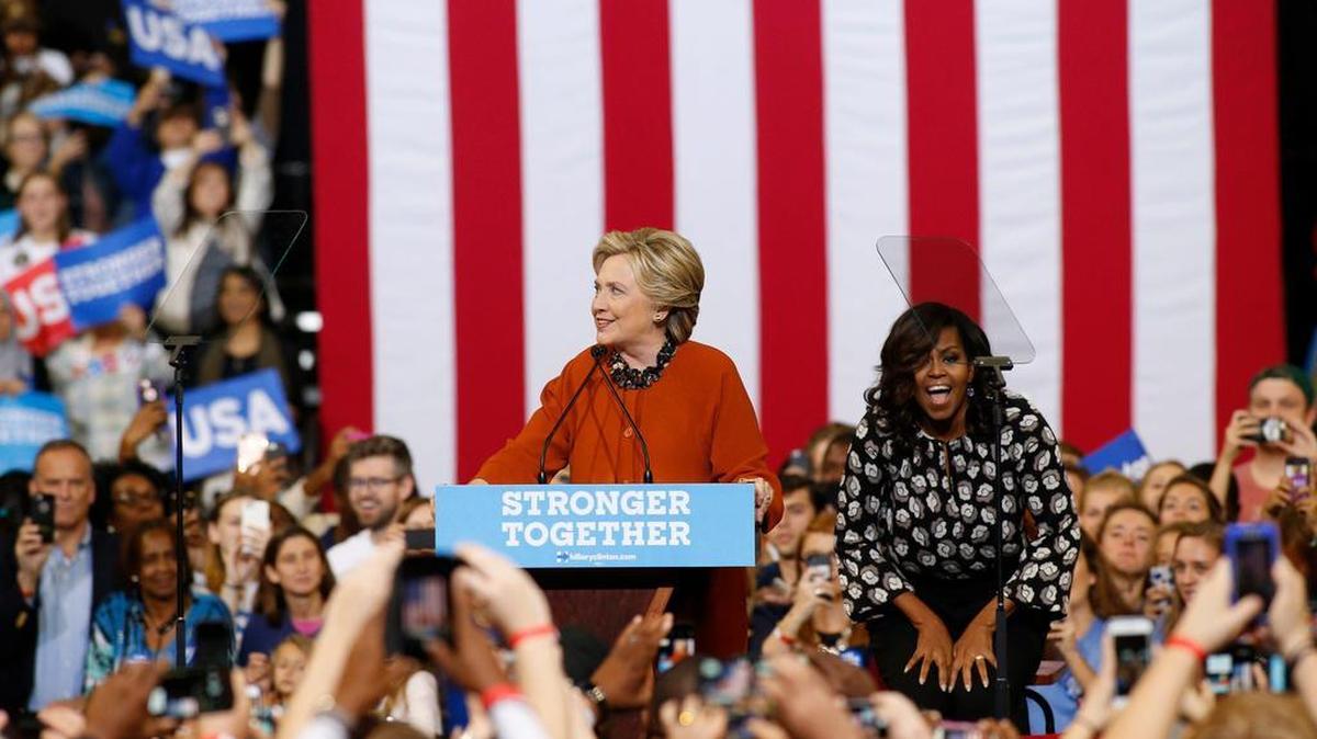 La candidata a la presidencia de EE.UU. por el partido Demócrata Hillary Clinton (c) habla junto a la primera dama de EE.UU. Michelle Obama (c-d) al cierre de un acto de campaña el jueves 27 de octubre 2016, en el Coliseo del Centro de Veteranos Lawrence Joel en Winston-Salem.