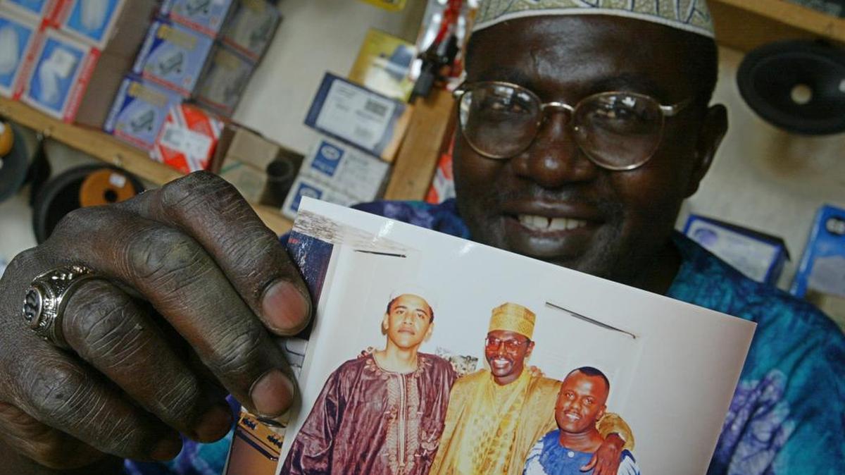 Malik Obama, el hermanastro mayor del presidente Barack Obama, muestra una foto de él con el presidente y un amigo, en esta imagen del 14 de septiembre de 2004, en Siaya, Kenia. Malike Obama ha dicho que piensa votar por Donald Trump.