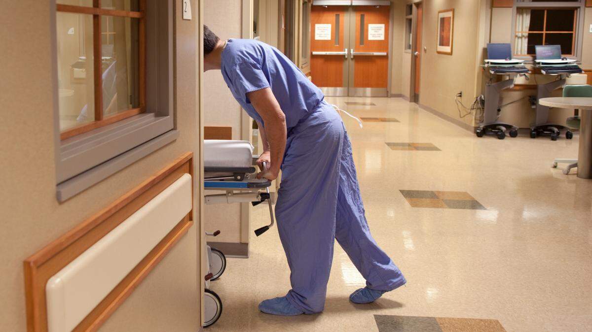 Foto ilustrativa - Un trabajador de la salud lleva la camilla de un paciente a la habitación de un paciente.