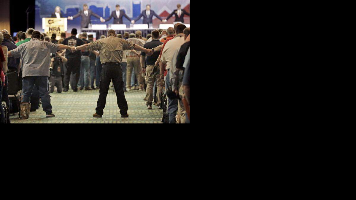 
Miembros de la Asociación Nacional del Rifle se toman de la mano y oran durante la apertura de la reunión anual de la organización en Nashville.
