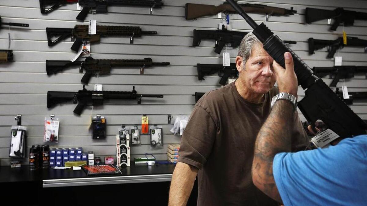 Frank Cobet, de la tienda de armas Get Loaded, en Chino, California, muestra a un cliente un rifle AR-15.