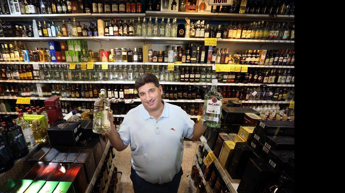
Eddie Cruz, dueño de cuatro licorerías en Miami, muestra con orgullo dos botellas de ron Bacardi en uno de sus locales, el jueves pasado.


