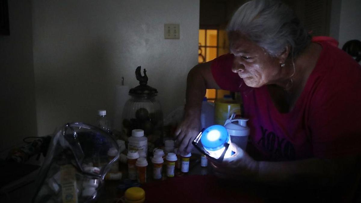 Melquiades Castellano usa una lámpara para mirar sus pastillas para su tratamiento de cáncer y presión arterial el 30 de septiembre de 2017 en San Juan, Puerto Rico. Ella y otros residentes de las 62 unidades de este condominio han estado sin electricidad después que pasó Huracán María.