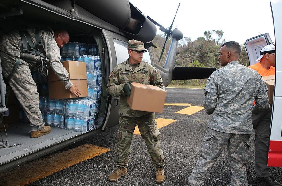 Ricardo Garratón (centro), coronel del Ejército de Estados Unidos, y un grupo de miembros de la Fuerza Aérea, descargan suministros tras aterrizar junto al Observatorio de Arecibo en un helicóptero, para entregar insumos en un poblado aislado en Carso, Puerto Rico.