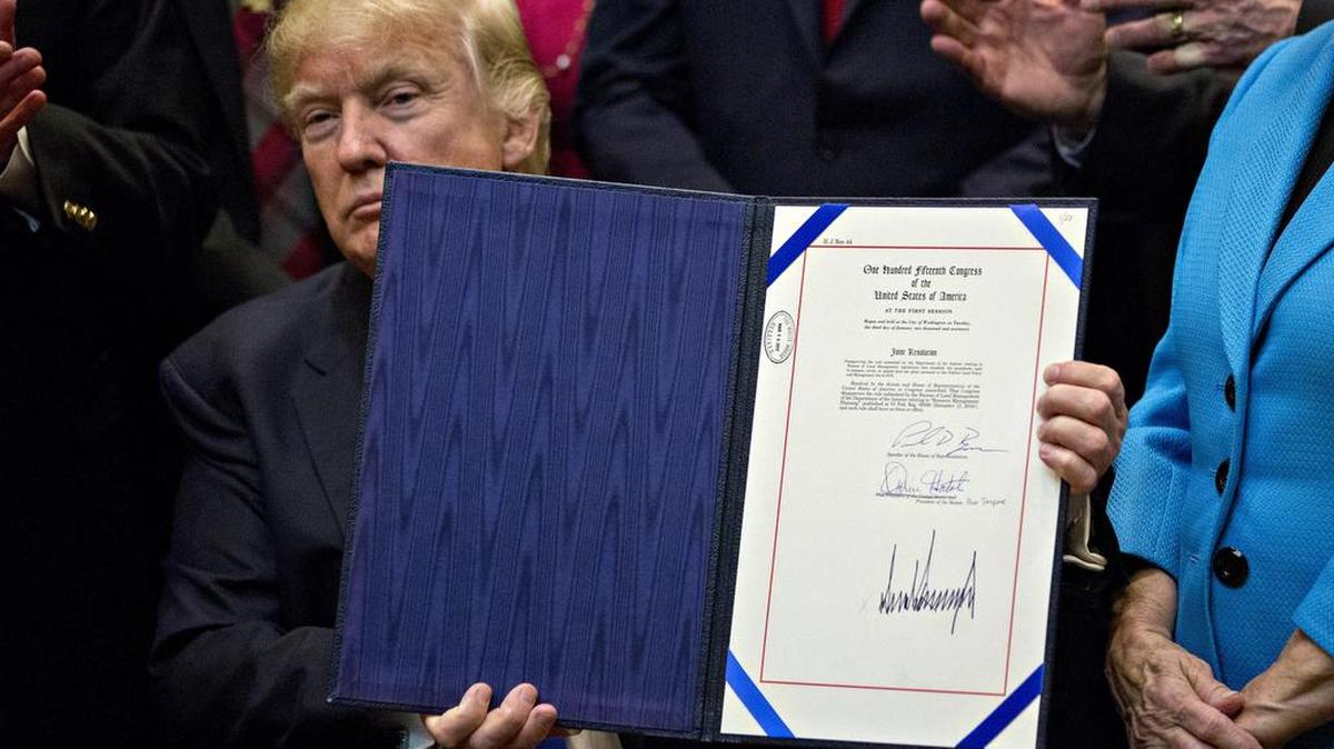 El presidente de Estados Unidos Donald Trump (C) muestra su firma a la resolución H.J. 44, que anula un proceso actualizado de planificación del uso de la tierra de la Oficina de Gestión de Tierras, durante una ceremonia de firma de un proyecto de ley en la Sala Roosevelt de la Casa Blanca en Washington, DC, (Estados Unidos) el lunes 27 de marzo de 2017.