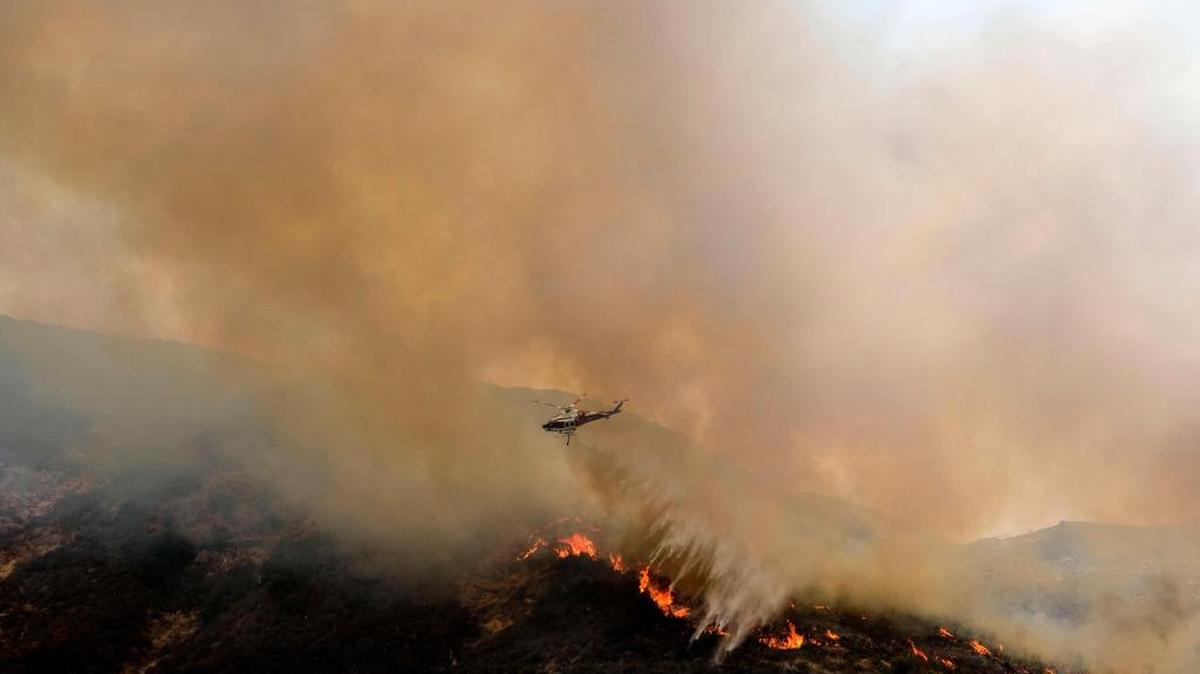 Un helicóptero arroja agua a un fuego de maleza en Holy Fire en Lake Elsinore, California, al sureste de Los Angeles, el 11 de agosto de 2018. - 