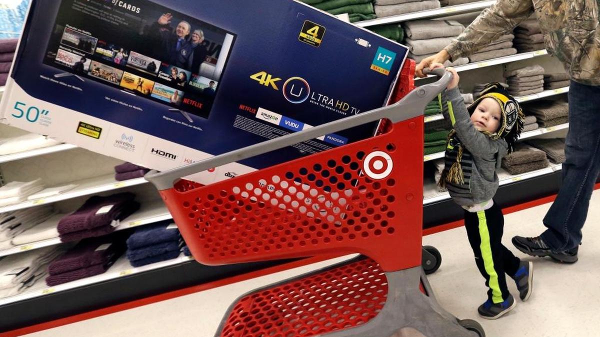 Hunter Harvey, de 2 años, ayuda a su padre, C.J., a empujar un carro de compras cargado con un televisor, en Target, en Wilmington, Massachusetts, el 29 de noviembre.
