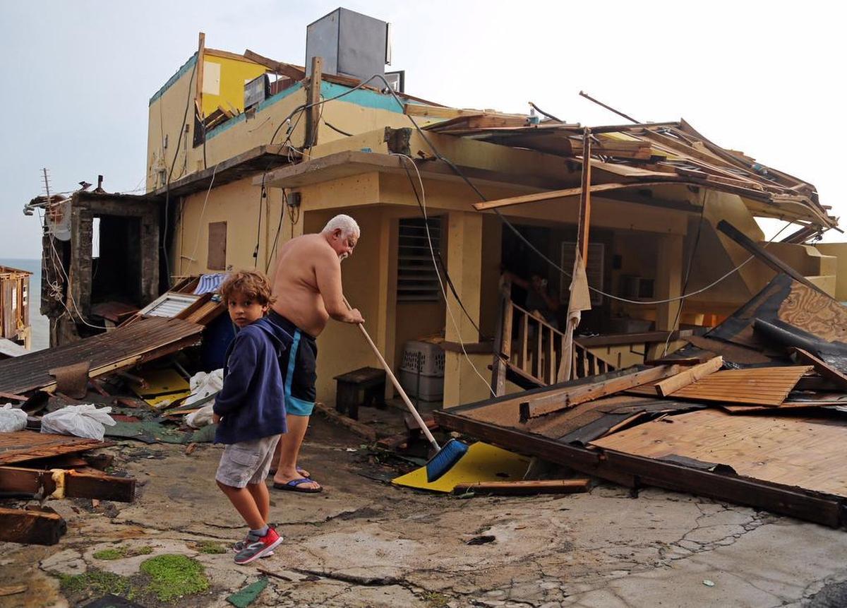 Luis Torres barre el frente de la casa de su madre en un suburbio de San Juan, que fue seriamente dañada por el huracán María.