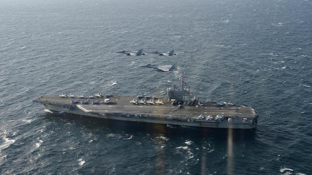 Dos aviones F/A-18 de EEUU y un F-15 de la Fuerza de Autodefensa del Aire de Japón vuelan sobre el portaaviones USS Ronald Reagan, para un ejercicio militar conjunto en un lugar no revelado.
