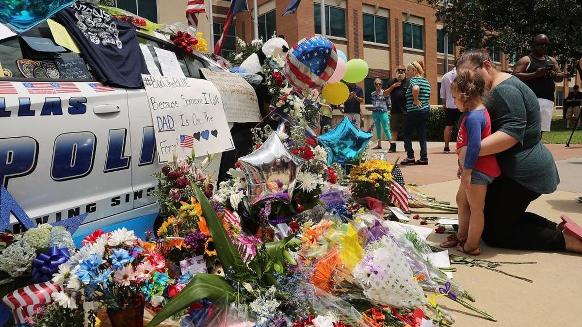 La gente pasa a dejar flores y otros objetos expresando su solidaridad con la Policía de Dallas por la pérdida de cinco de sus efectivos el jueves.