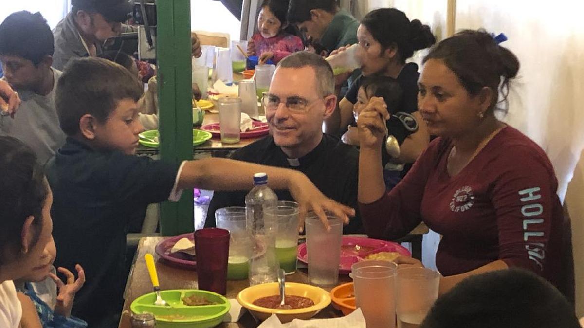 El sacerdote jesuíta Sean Carroll se une a un grupo de migrantes hondureños en la cafetería que administra en Nogales, México, para las personas que buscan asilo en la frontera con Estados Unidos.