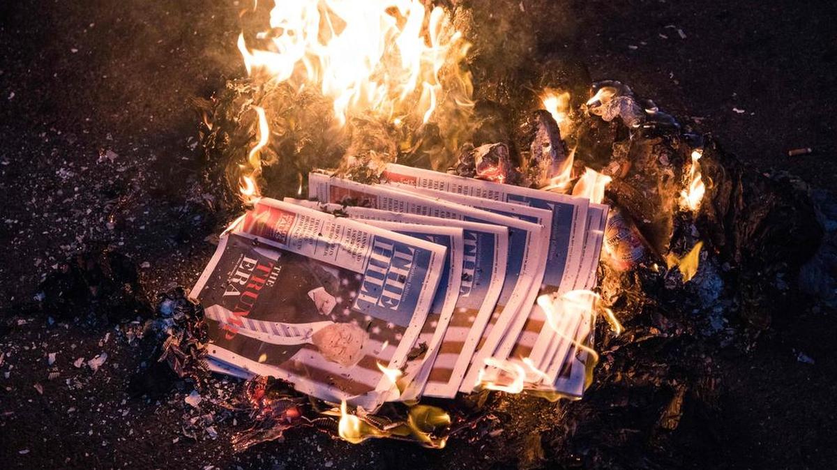 Copias de un periódico con Donald Trump en la primera página se prendieron en fuego después de la inauguración del Presidente Trump el 20 de enero de 2017 en Washington, DC.
