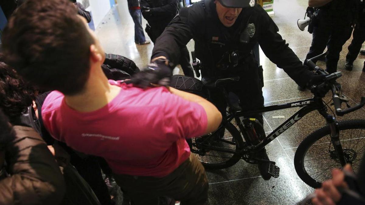 Un policía de Seattle empuja a un manifestante el domingo en el Aeropuerto Internacional Seattle-Tacoma de esa ciudad.