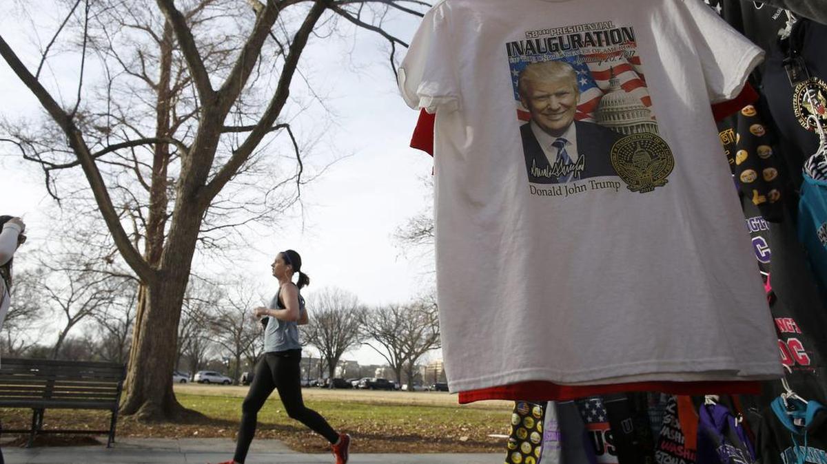 Una joven corre junto a un puesto callejero en el que se venden camisetas para la investidura del presidente electo, Donald Trump, en Washington DC (Estados Unidos) el 12 de enero de 2017.